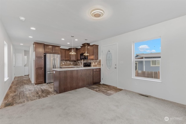 kitchen with stainless steel fridge, pendant lighting, carpet flooring, and tasteful backsplash