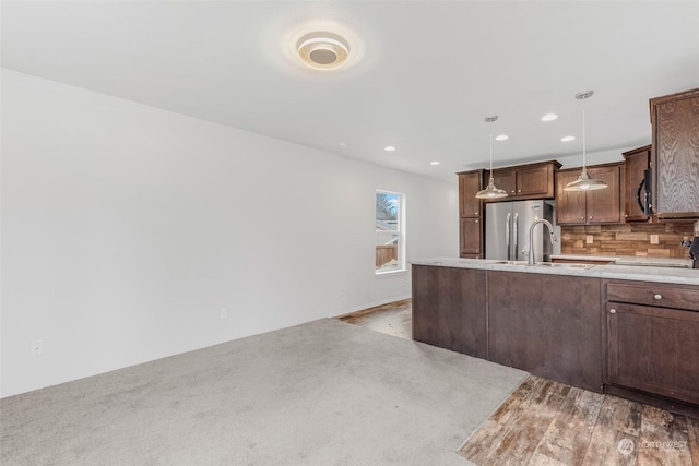 kitchen featuring decorative light fixtures, sink, stainless steel refrigerator, and tasteful backsplash