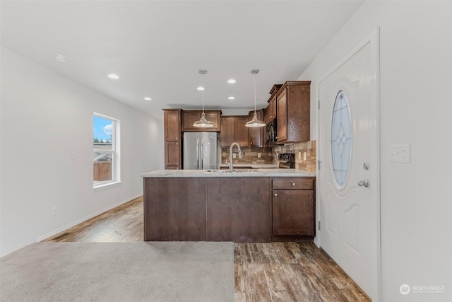 kitchen featuring black appliances, sink, decorative backsplash, decorative light fixtures, and wood-type flooring