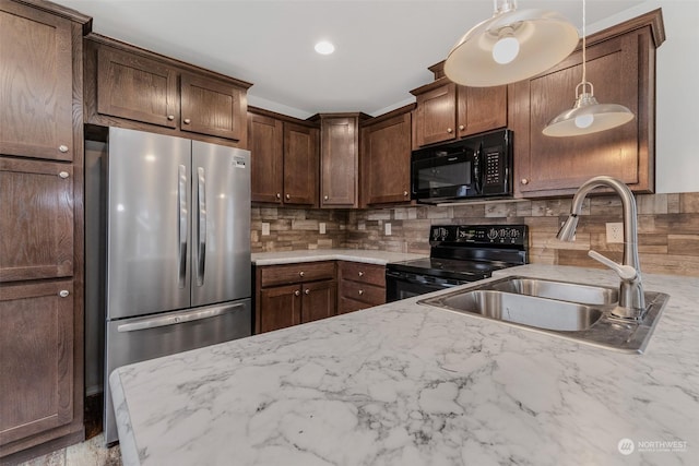 kitchen featuring light stone countertops, tasteful backsplash, sink, black appliances, and pendant lighting