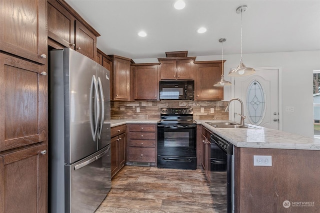 kitchen with tasteful backsplash, dark wood-type flooring, sink, black appliances, and pendant lighting