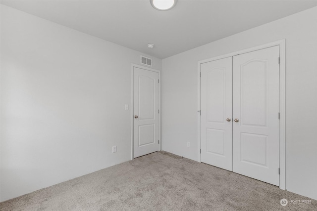 unfurnished bedroom featuring light carpet and a closet