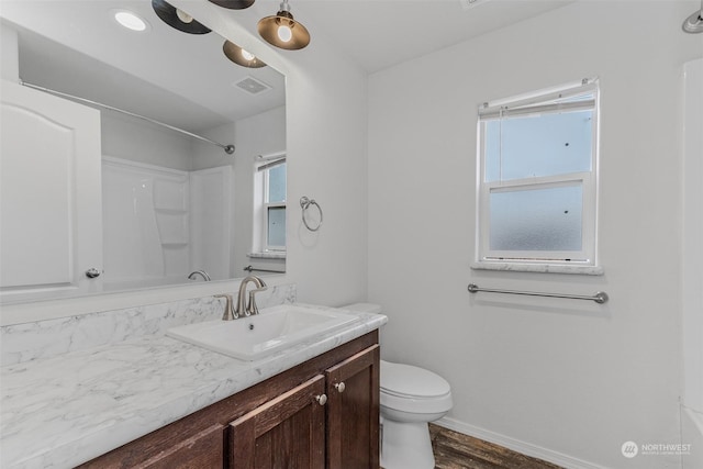 bathroom with hardwood / wood-style floors, vanity, toilet, and a shower