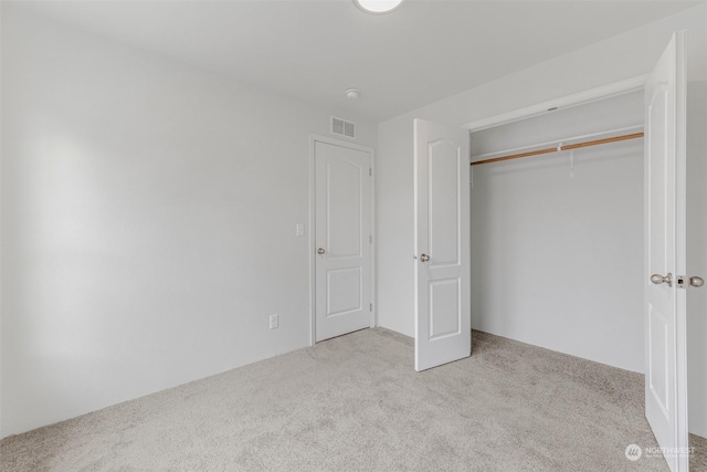 unfurnished bedroom with a closet and light colored carpet