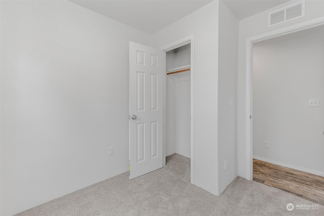 unfurnished bedroom with light carpet and a closet