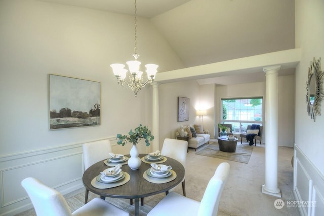 dining space with carpet floors, high vaulted ceiling, ornate columns, and a notable chandelier