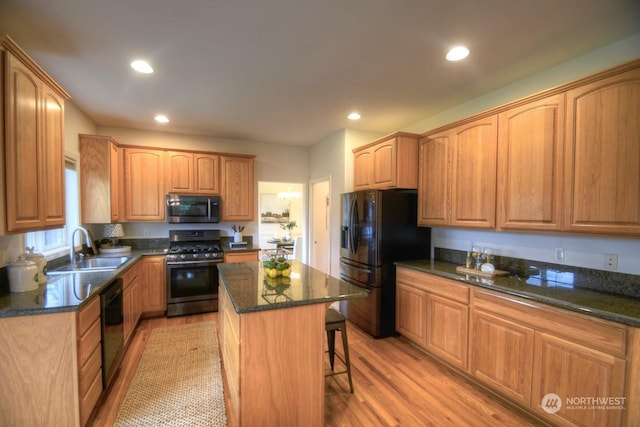 kitchen with a breakfast bar, sink, black appliances, light hardwood / wood-style flooring, and a center island