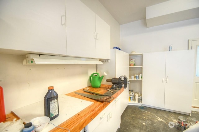 kitchen with butcher block counters and white cabinetry