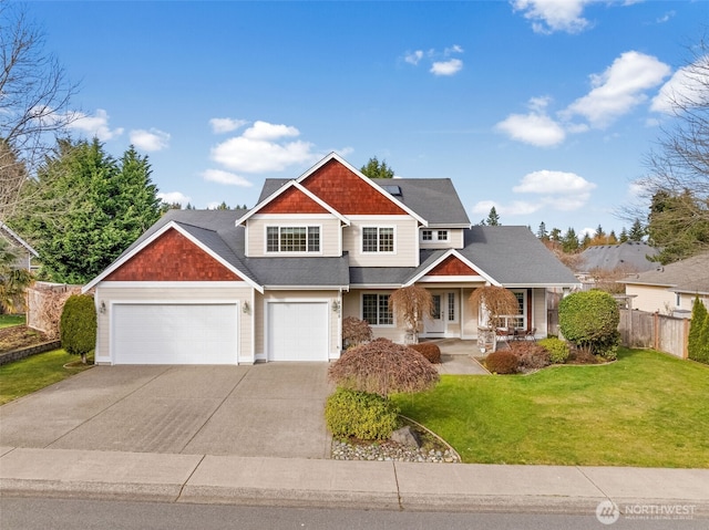 craftsman-style home featuring driveway, fence, and a front lawn