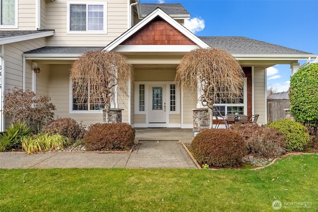 entrance to property with a porch and roof with shingles