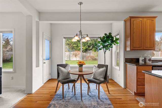 dining room featuring baseboards, light wood-type flooring, and an inviting chandelier