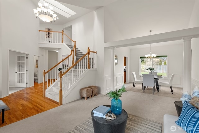 living area featuring stairs, a high ceiling, carpet floors, a decorative wall, and a notable chandelier