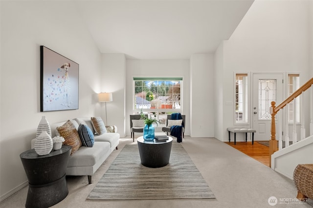 carpeted living area with lofted ceiling and stairway