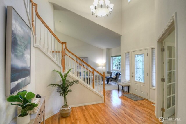 entrance foyer featuring a chandelier, wood finished floors, a high ceiling, and stairs