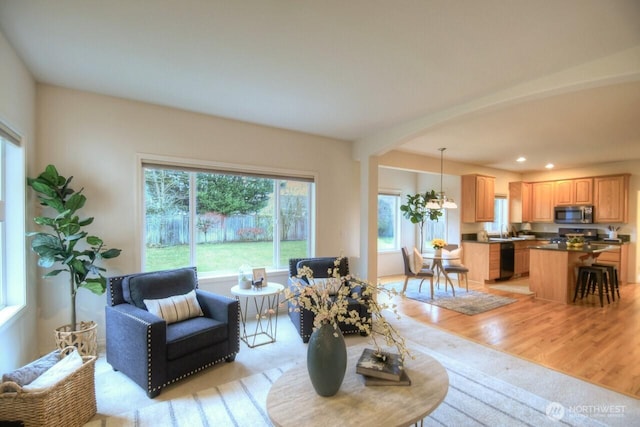 living room featuring light wood-style floors, arched walkways, and recessed lighting