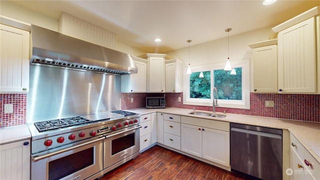 kitchen with sink, stainless steel appliances, wall chimney range hood, pendant lighting, and decorative backsplash