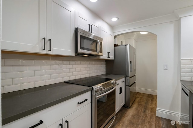 kitchen featuring decorative backsplash, white cabinetry, dark hardwood / wood-style flooring, and appliances with stainless steel finishes