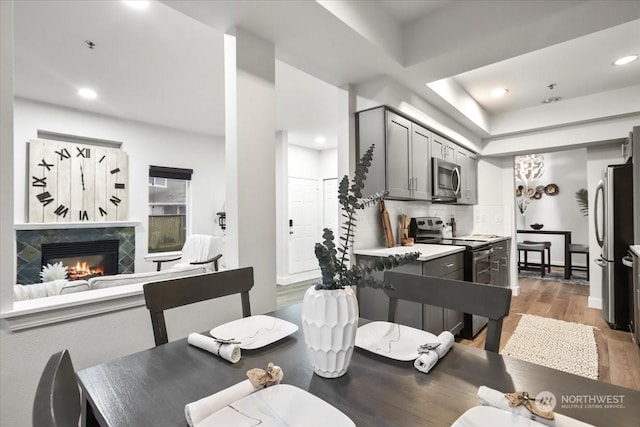 dining area featuring a premium fireplace, a raised ceiling, and light hardwood / wood-style floors