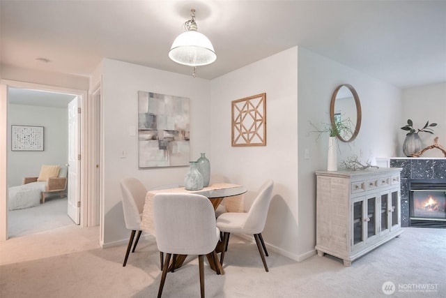 carpeted dining room with a glass covered fireplace and baseboards