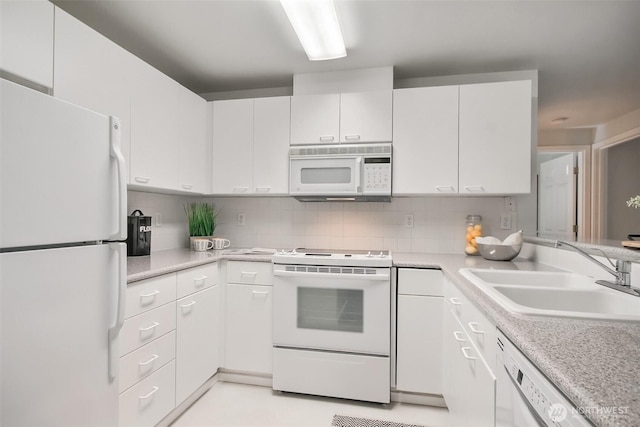 kitchen with white appliances, white cabinetry, light countertops, and a sink