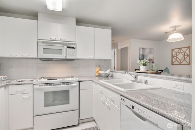 kitchen with white appliances, decorative backsplash, a peninsula, white cabinetry, and a sink