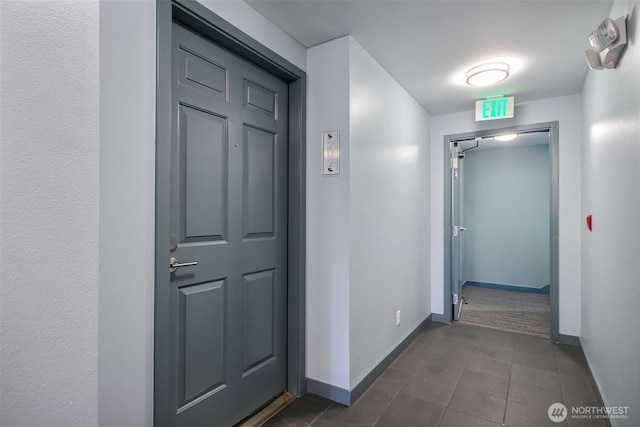 hall with dark tile patterned flooring and baseboards