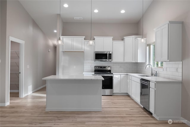 kitchen with sink, decorative light fixtures, a kitchen island, white cabinetry, and stainless steel appliances