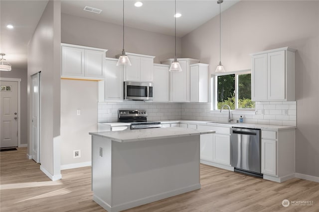 kitchen featuring white cabinets, appliances with stainless steel finishes, a kitchen island, and sink