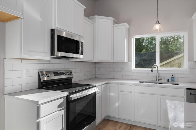 kitchen with backsplash, stainless steel appliances, sink, light hardwood / wood-style floors, and white cabinetry