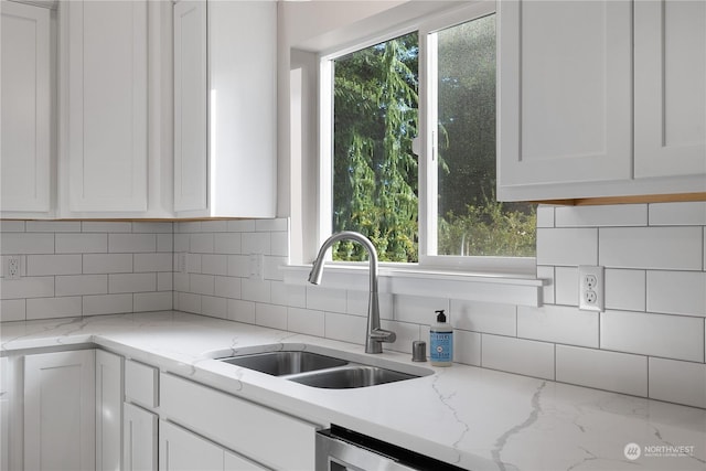 kitchen featuring white cabinets, backsplash, and sink