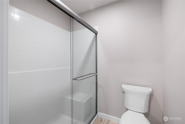 bathroom featuring wood-type flooring, toilet, and an enclosed shower