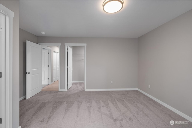 unfurnished bedroom featuring light colored carpet, a spacious closet, and a closet