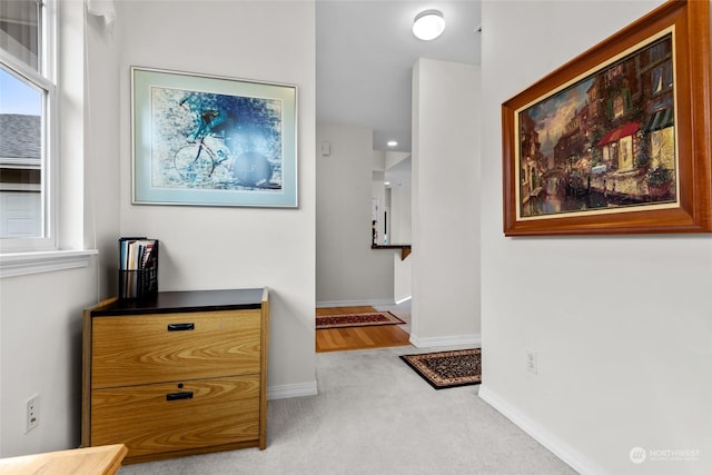 hall featuring light colored carpet and plenty of natural light