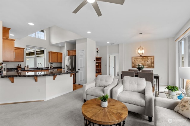 carpeted living room with ceiling fan with notable chandelier