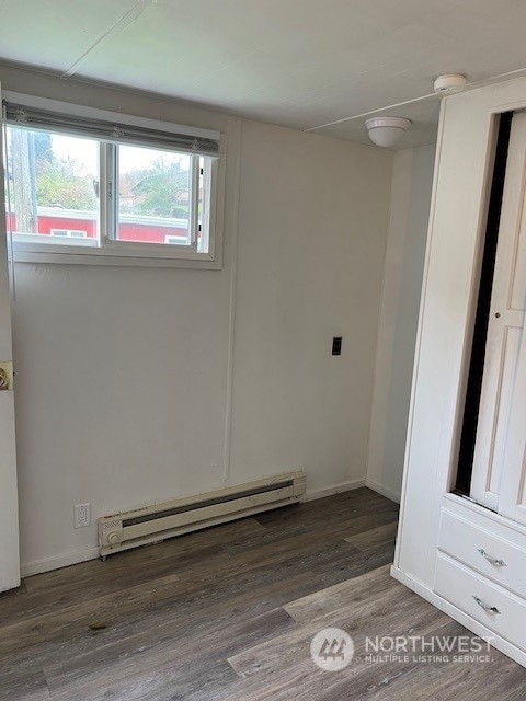 empty room featuring a baseboard radiator and dark hardwood / wood-style floors