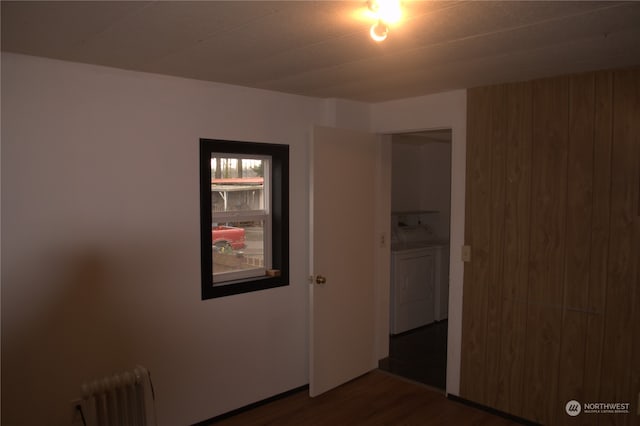 empty room with radiator, washer and dryer, and dark hardwood / wood-style floors