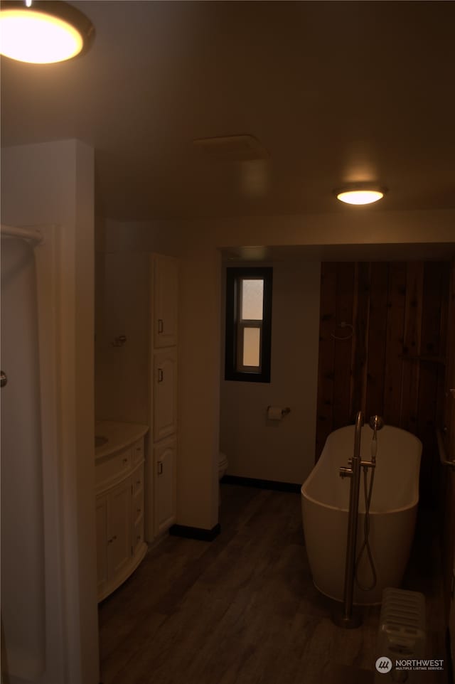 bathroom with hardwood / wood-style floors, toilet, and a tub