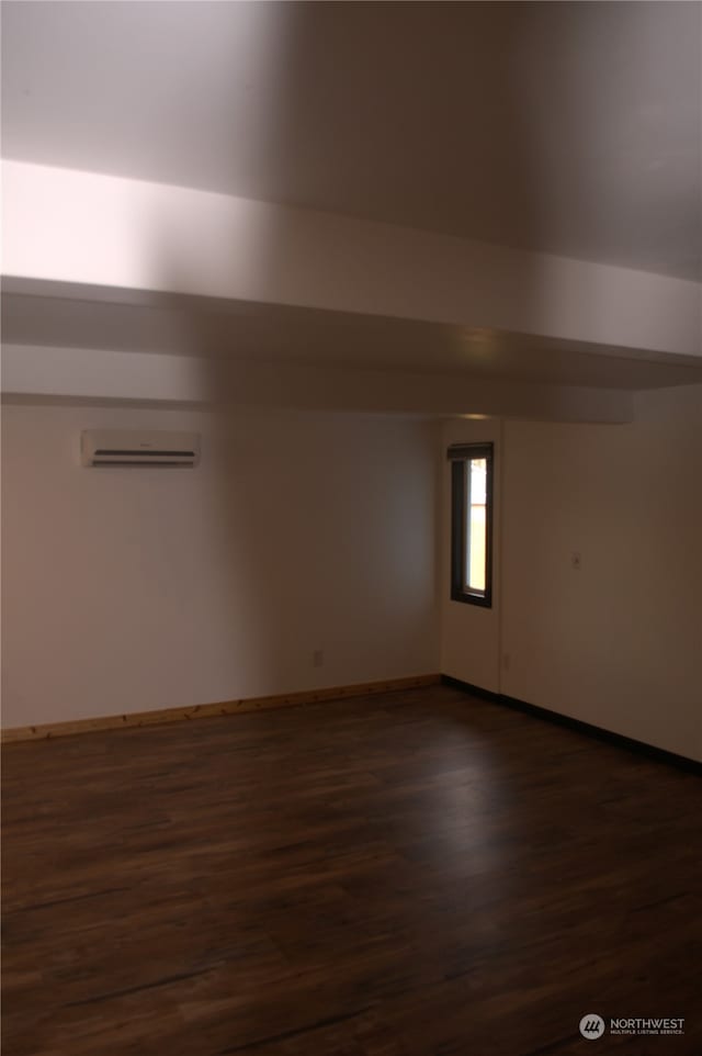 spare room with a wall mounted air conditioner and dark wood-type flooring