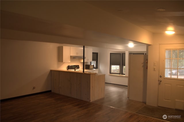 kitchen with kitchen peninsula, dark wood-type flooring, black range, white cabinets, and white fridge