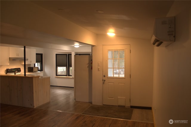 doorway featuring a wall mounted air conditioner, dark hardwood / wood-style floors, and vaulted ceiling