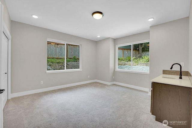 unfurnished bedroom with light colored carpet, a sink, baseboards, and recessed lighting