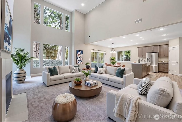 living area with a high ceiling, recessed lighting, baseboards, and a chandelier
