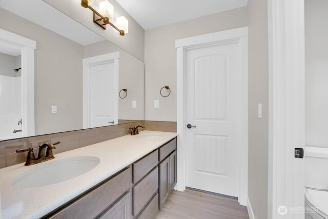 full bathroom with tasteful backsplash, toilet, double vanity, and wood finished floors