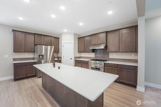 kitchen featuring high end appliances, under cabinet range hood, baseboards, light countertops, and recessed lighting