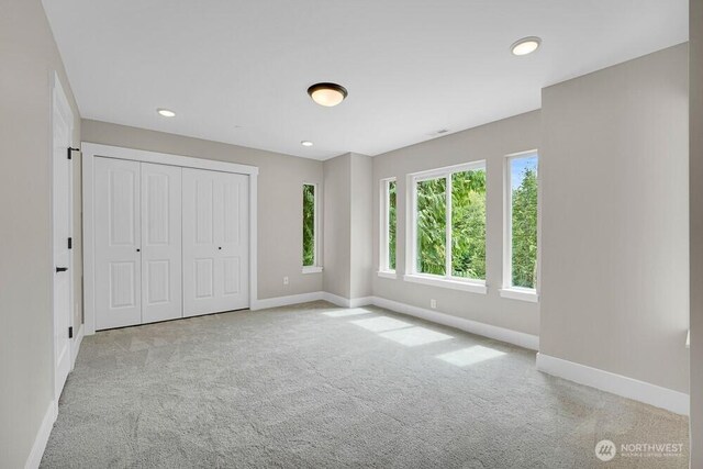 unfurnished bedroom featuring baseboards, carpet, recessed lighting, and a closet