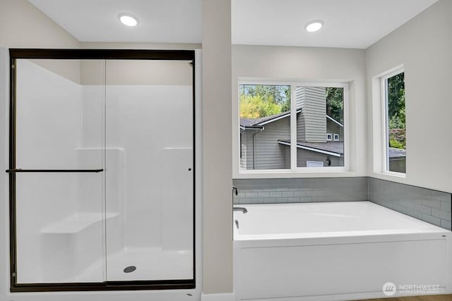 bathroom with a shower stall, healthy amount of natural light, and a bath