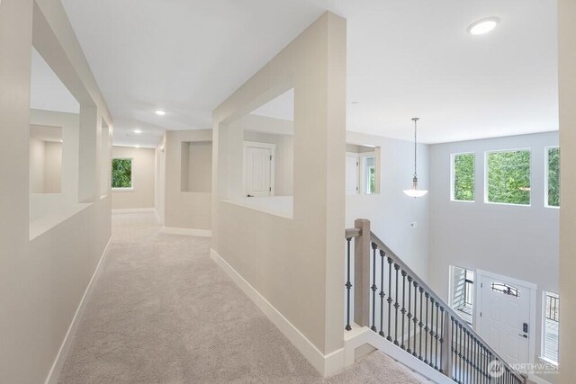 hallway with an upstairs landing, baseboards, carpet, and recessed lighting
