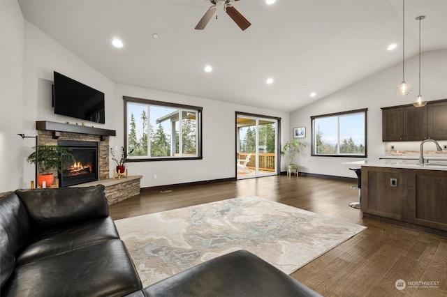 living room with a fireplace, sink, dark hardwood / wood-style floors, vaulted ceiling, and ceiling fan