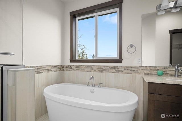 bathroom with tile walls, vanity, and a bathing tub