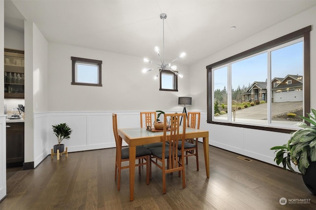 dining room with dark hardwood / wood-style floors and a notable chandelier